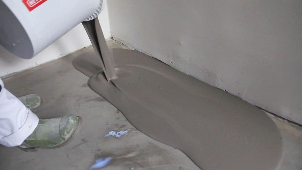 Person som holder på med avretting på gulv av betong.