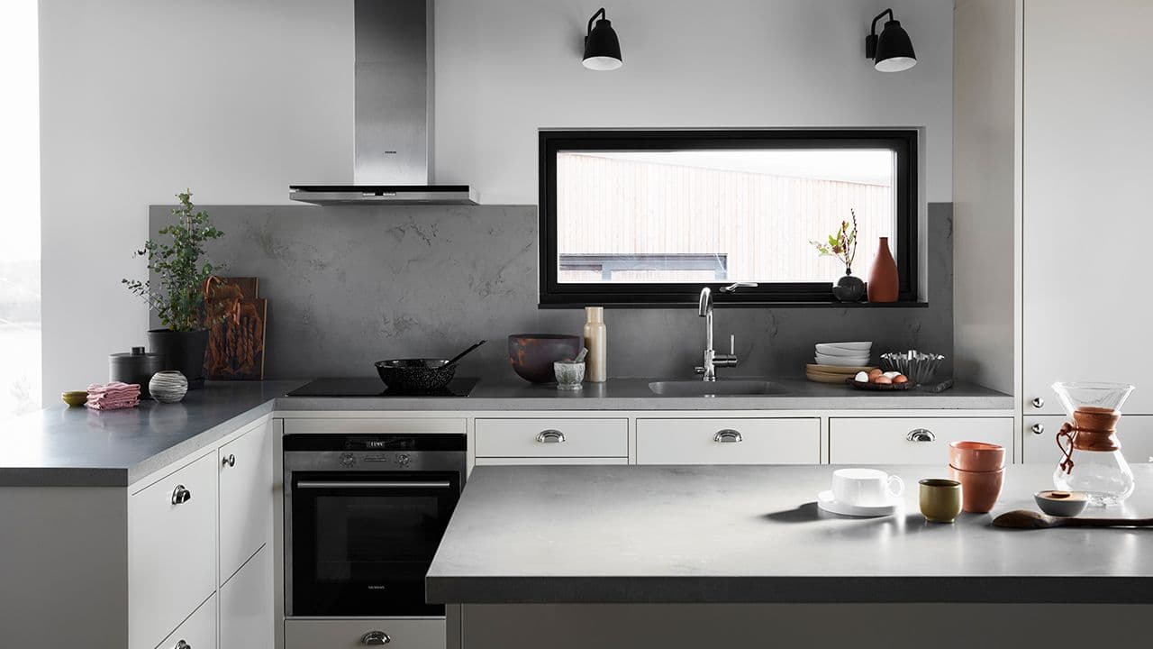 Integrerte hvitevarer gjemt i skap og bak kjøkkenøy i lyst kjøkken.