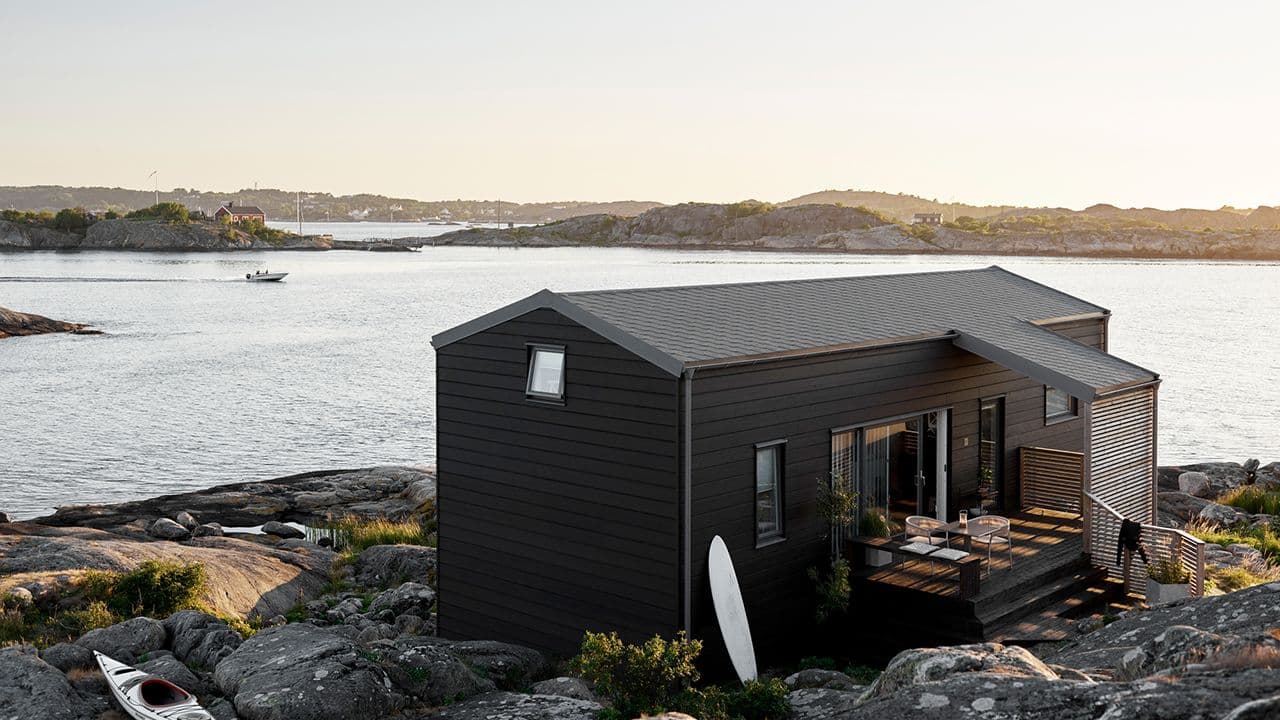 Hytte ved sjøen malt med hybridmaling Jotun DRYGOLIN Color Expert i fargen 9938 Dempet Sort..