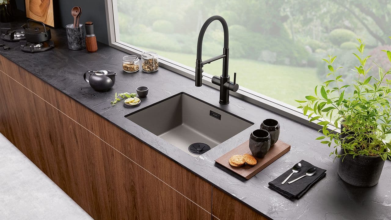 Svart blandebatteri som matcher benkeplaten på kjøkkenet.