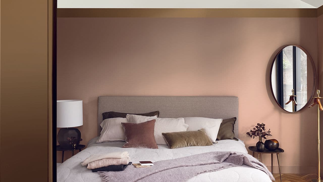 Soverom med dobbeltseng og ulike brune trendfarger på veggene.