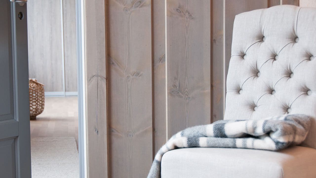 Panelvegg og dør, med en stol i front av bildet.