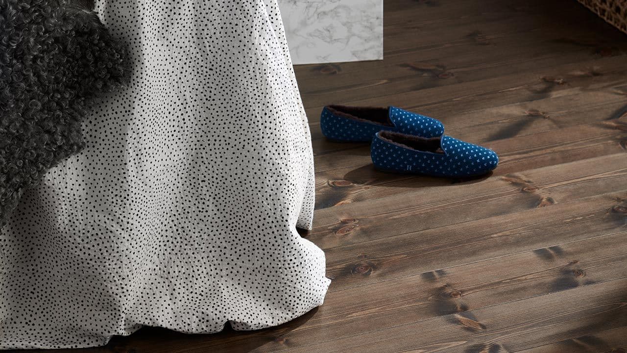 Mørke tregulv i soverom og blå tøfler.