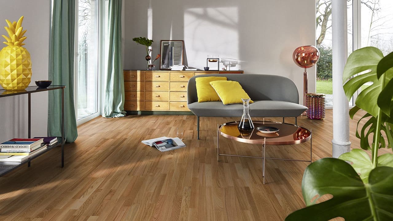 Eik Vivace gulv fra BOEN i stue med grå moderne sofa og kobberbord.