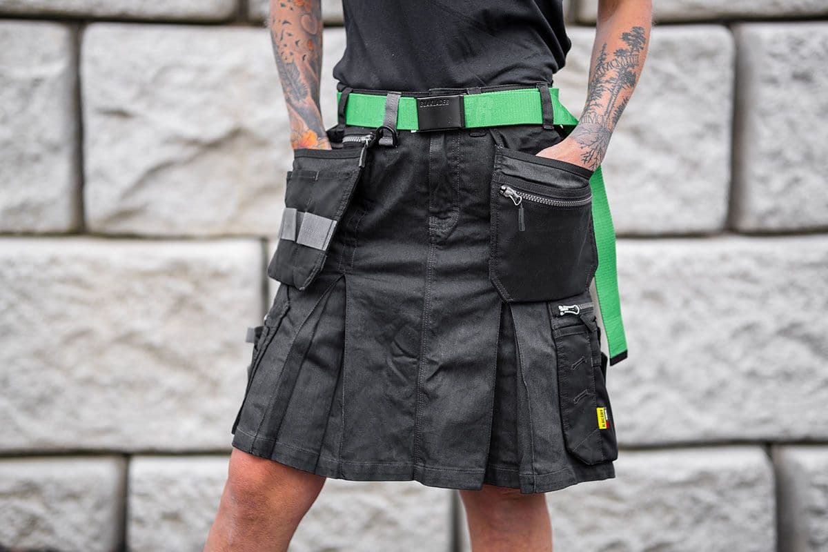 Nærbilde av en kvinnelig snekker i håndverkerskjørt fra Blåkläder med grønt belte.