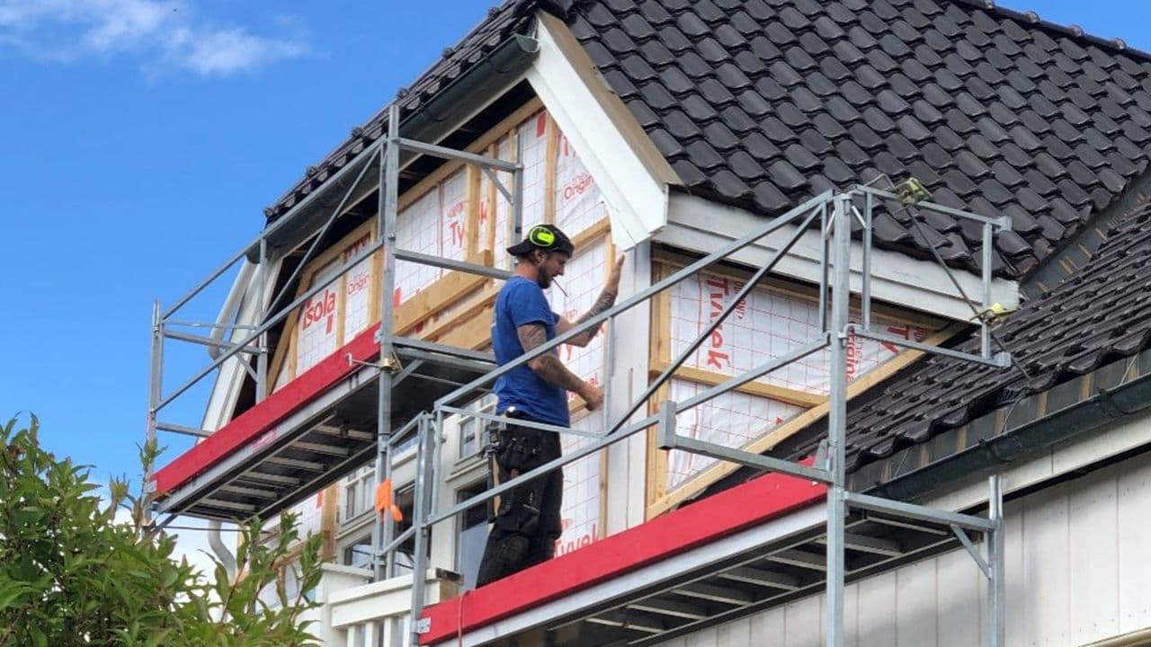 Håndverker som monterer vindsperre på hus.