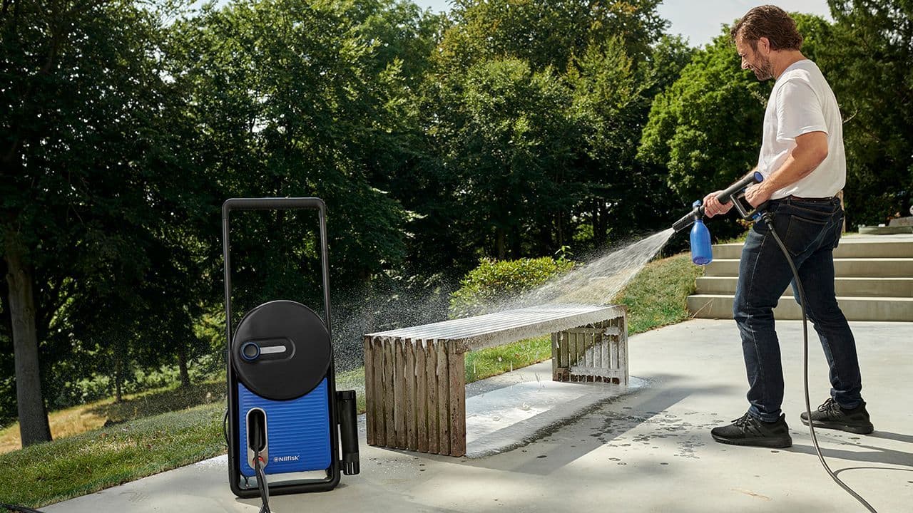 En mann vasker ute med et Nilfisk produkt