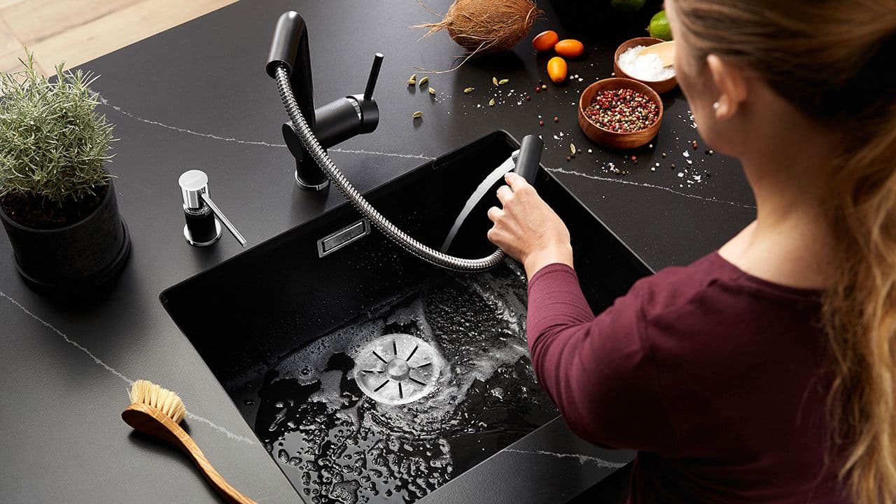 Kvinne som holder blandebatteri med uttrekkbart dusjhode, en av mange smarte løsning på kjøkkenet.