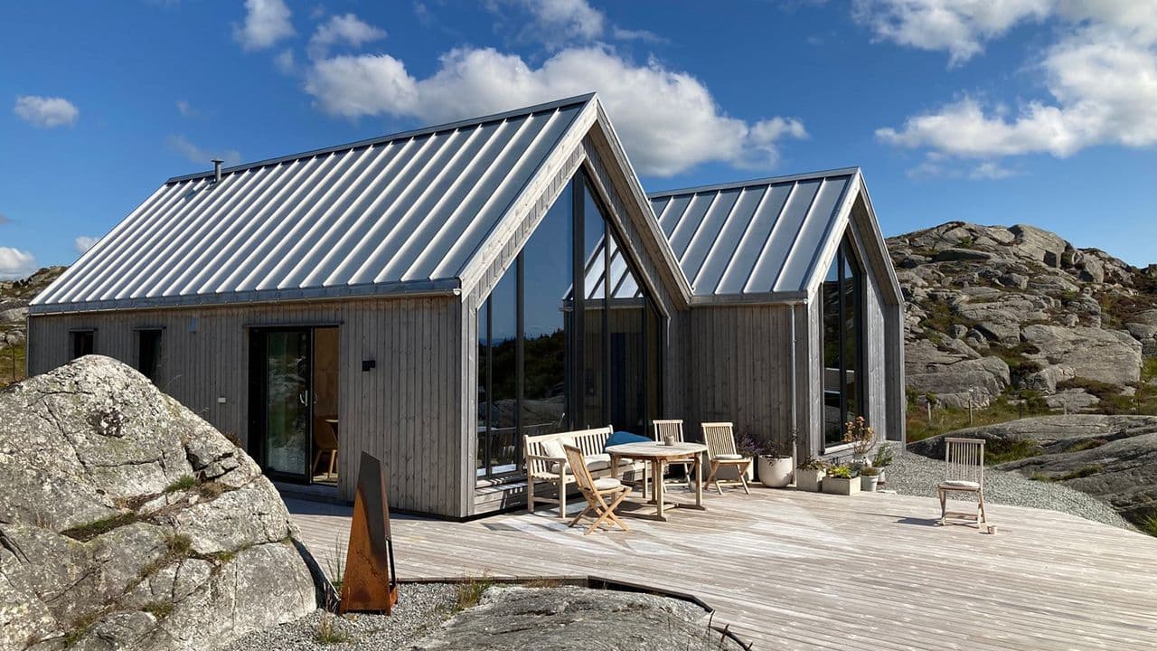 Hytte med store vinduer mot sjøen.
