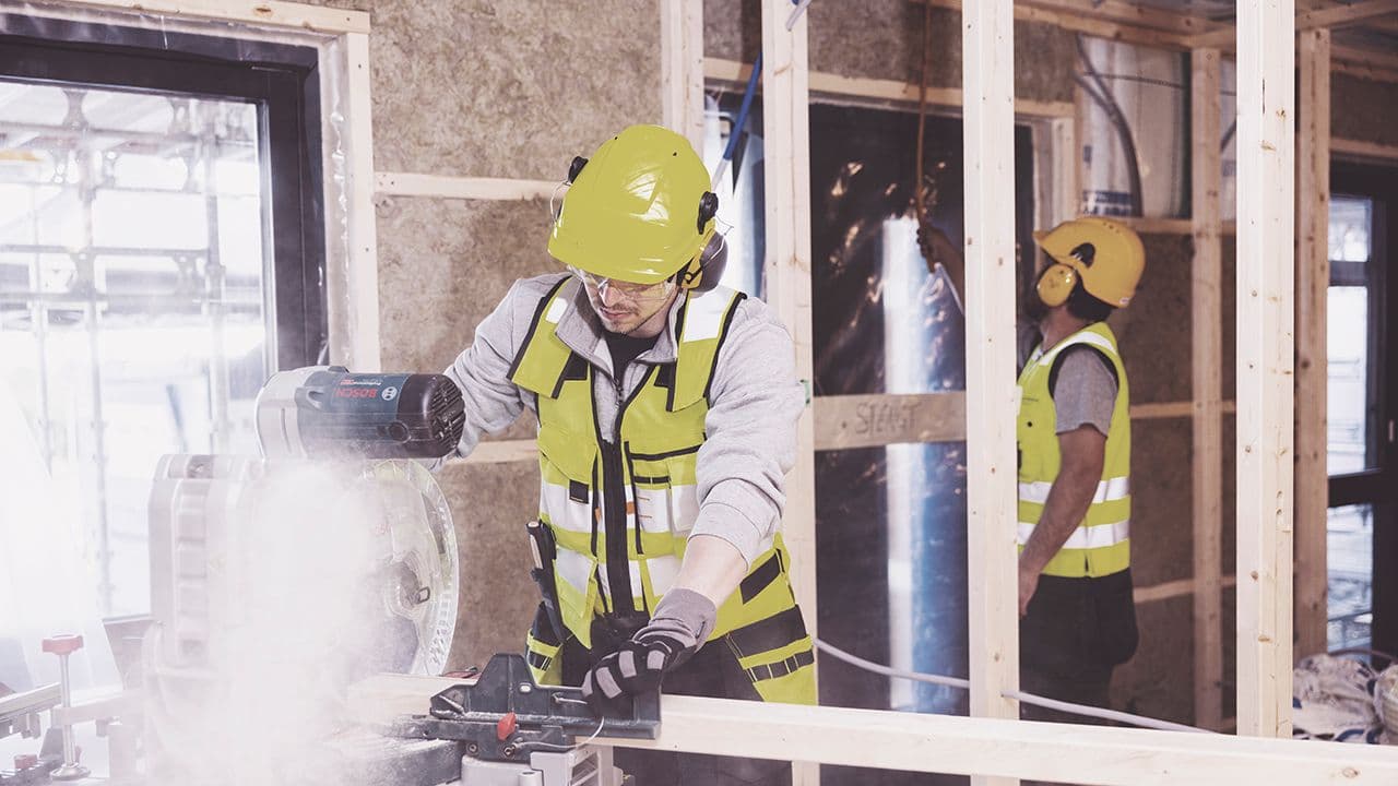Håndverkere med hjelm inne på byggeplass.