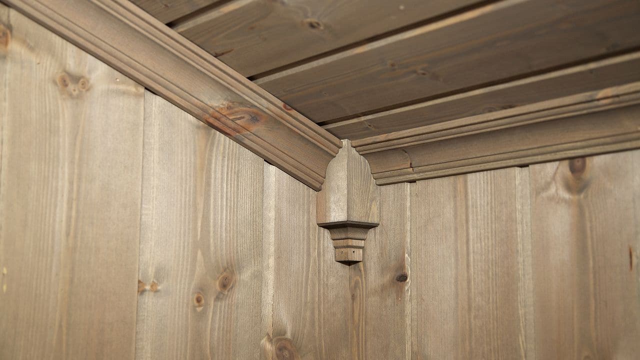 Profilerte taklister med hjørnekloss i samme farge som panel på vegg og i taket.