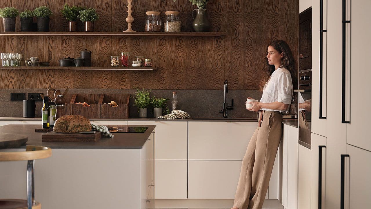 Dame som lener seg inntil kjøkkenbenken