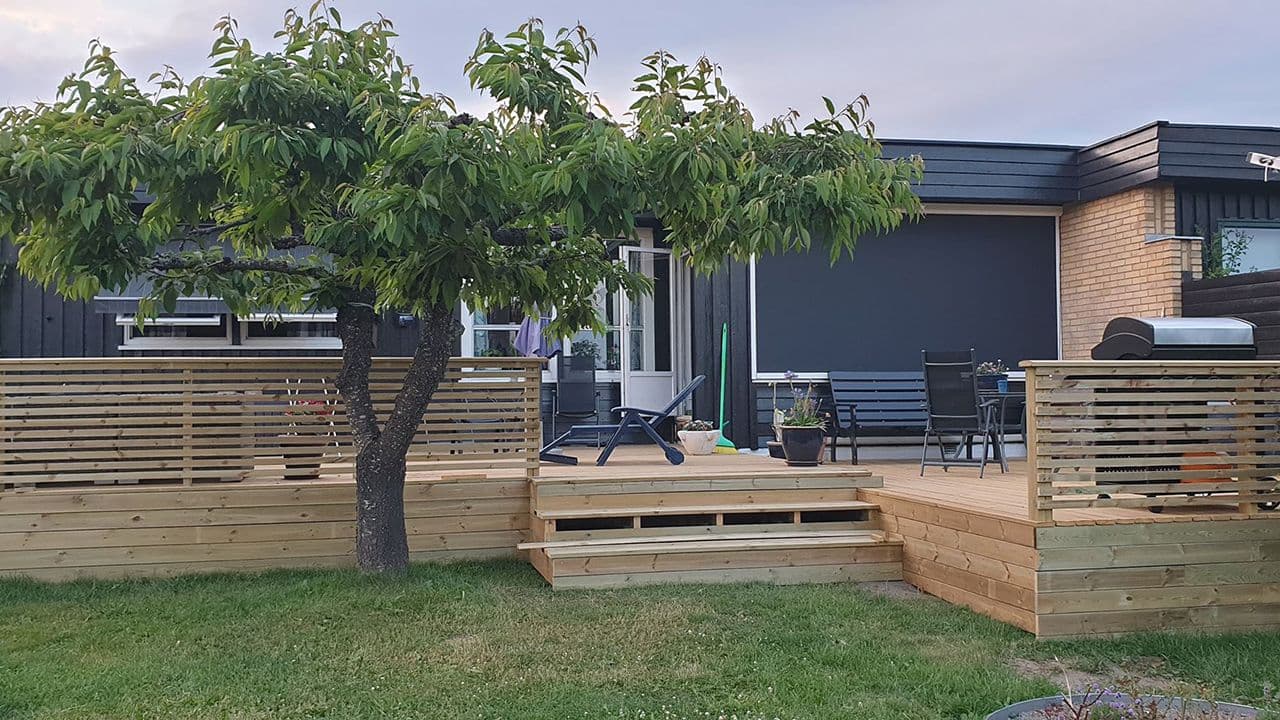 Terrasse med trapp til hage, rekkverk og sittegruppe.