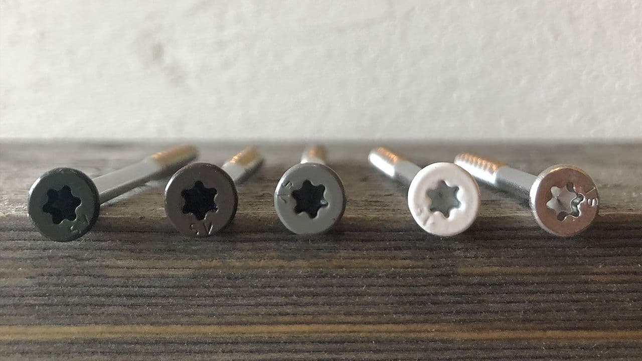 Detaljbilde av fasadeskruer i ulike farger: Sort, brun, grå, hvit og ulakkert.