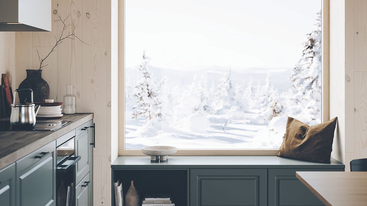 Mørkt hyttekjøkken med sittebenk foran vinduet.