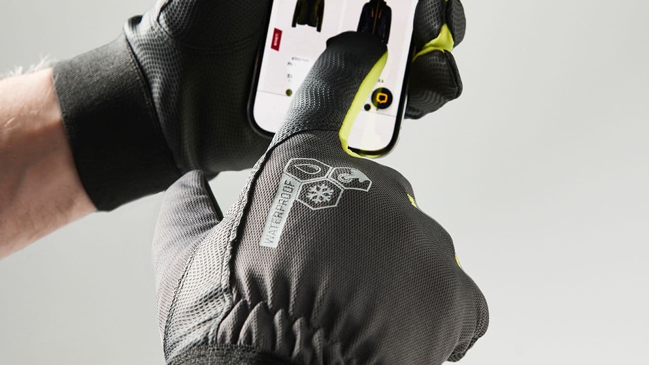 Mann med arbeidshansker som trykket på skjermen på en smarttelefon.