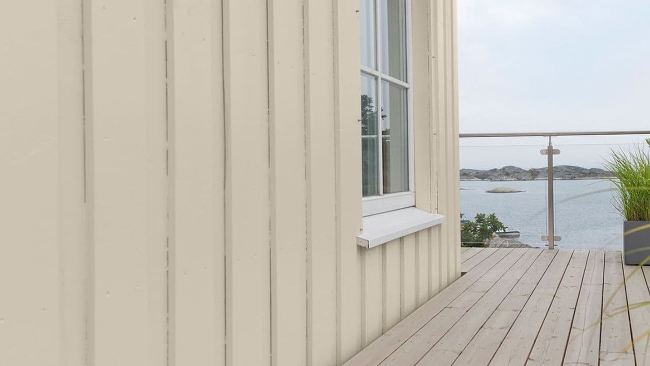 Lys ferdig malt utvendig kledning på hus ved sjøen.