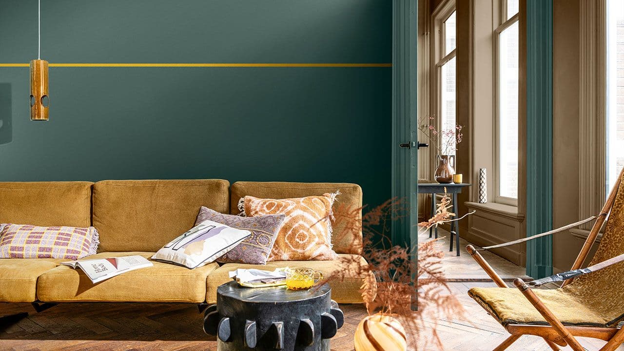 Stue malt i mørk dyp grønnfarge med sofa i gul kontrast.