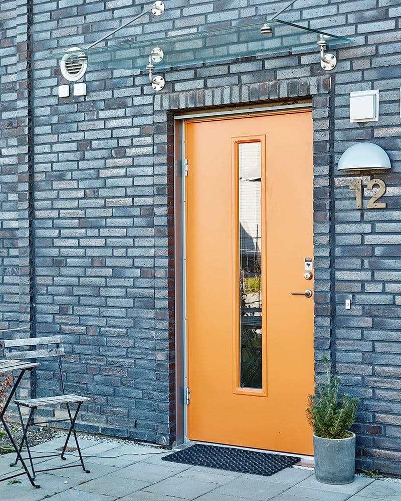 Knall oransje ytterdør fra Swedoor med vindusfelt i en mursteinsbygning