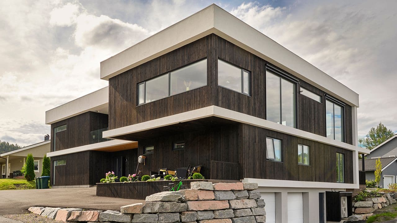 Moderne hus med mørk brun kledning.