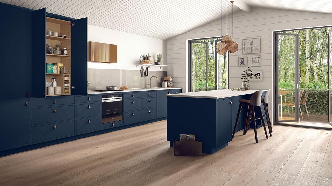 Blått kjøkken med over- og underskap og hvitevarer plassert i høyskap.