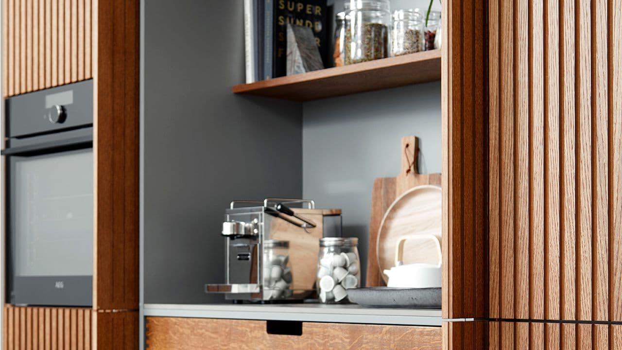 Kjøkken i treverk med pocket-dører som skjuler oppbevaring.