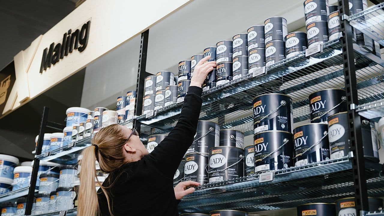 XL-BYGG ansatt henter Jotun maling fra hyllene i butikken.