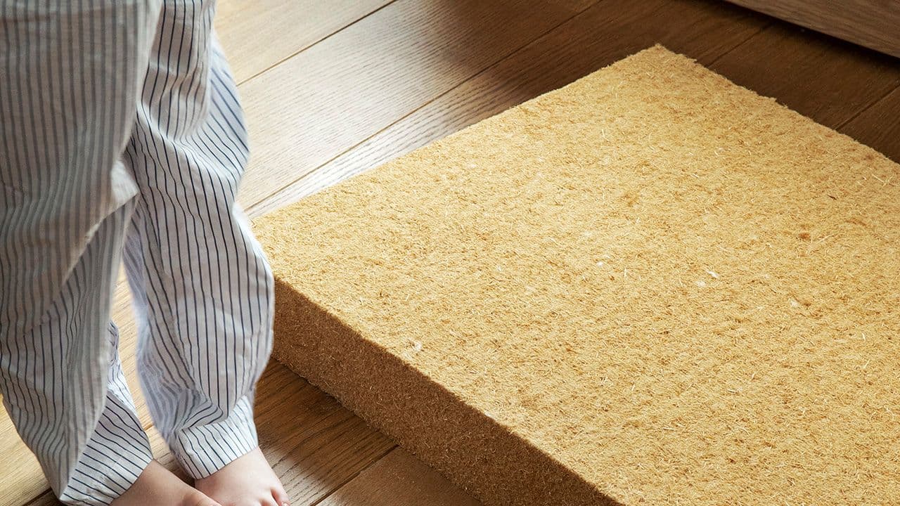 Trefiber-isolasjonsplate som ligger på gulvet ved siden av en person.