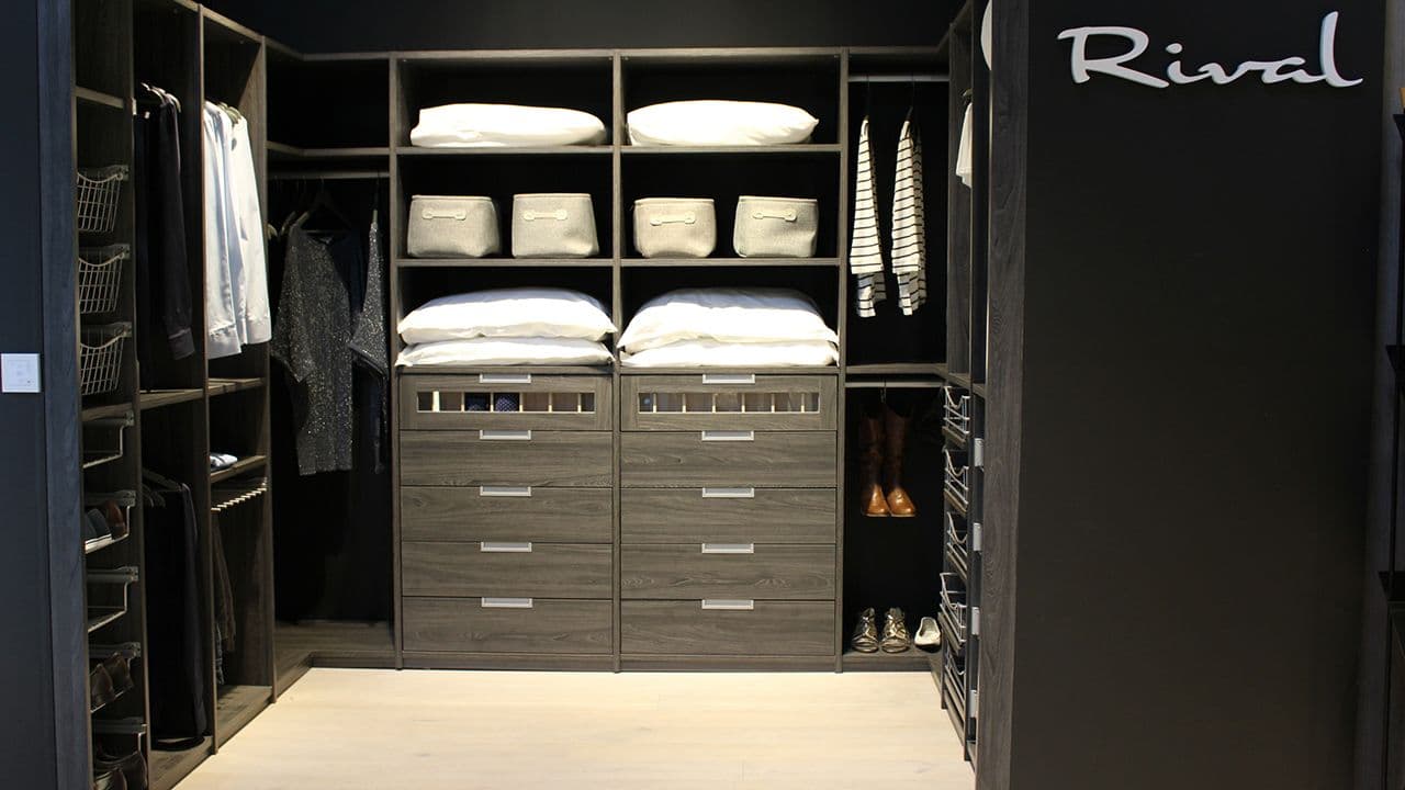 Sort walk-in-garderobe med lyst tregulv.