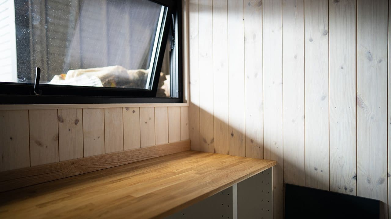 Hyttekjøkken med lys furupanel og kjøkkenvindu.