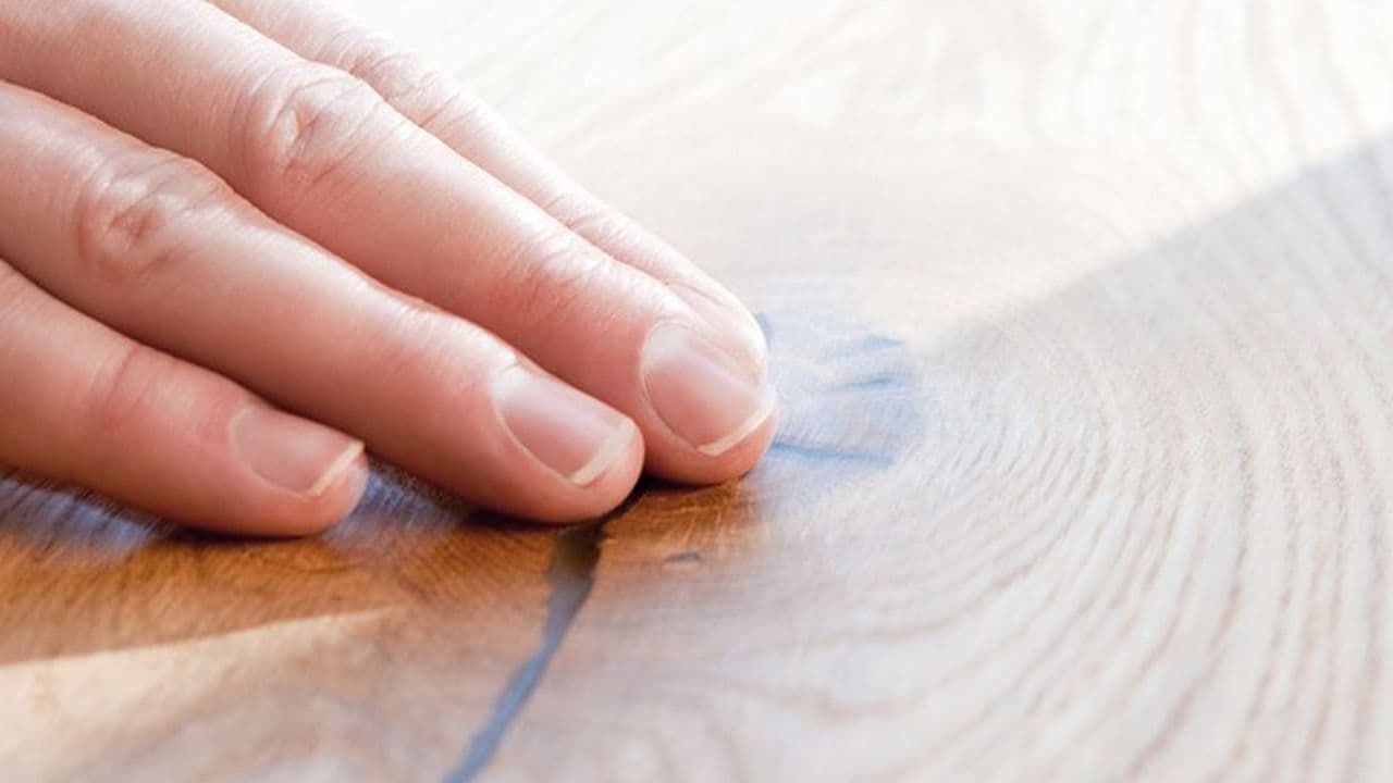 Fingre som berører gulv i laminat.