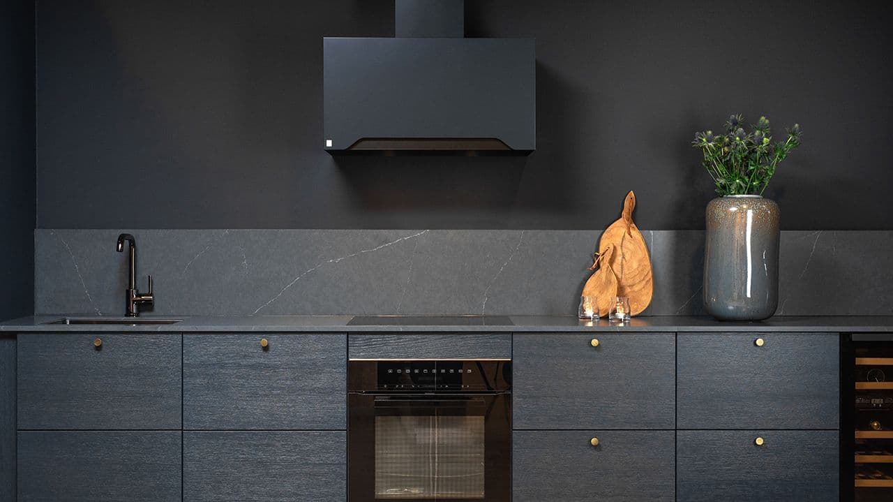 Svart kjøkken med gull på håndtak.