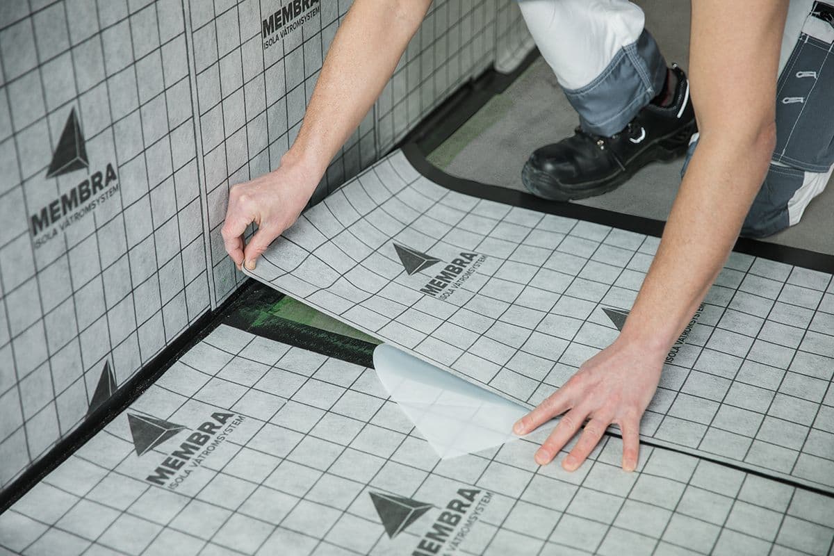 mann legger Membra våtromssystem på et badegulv