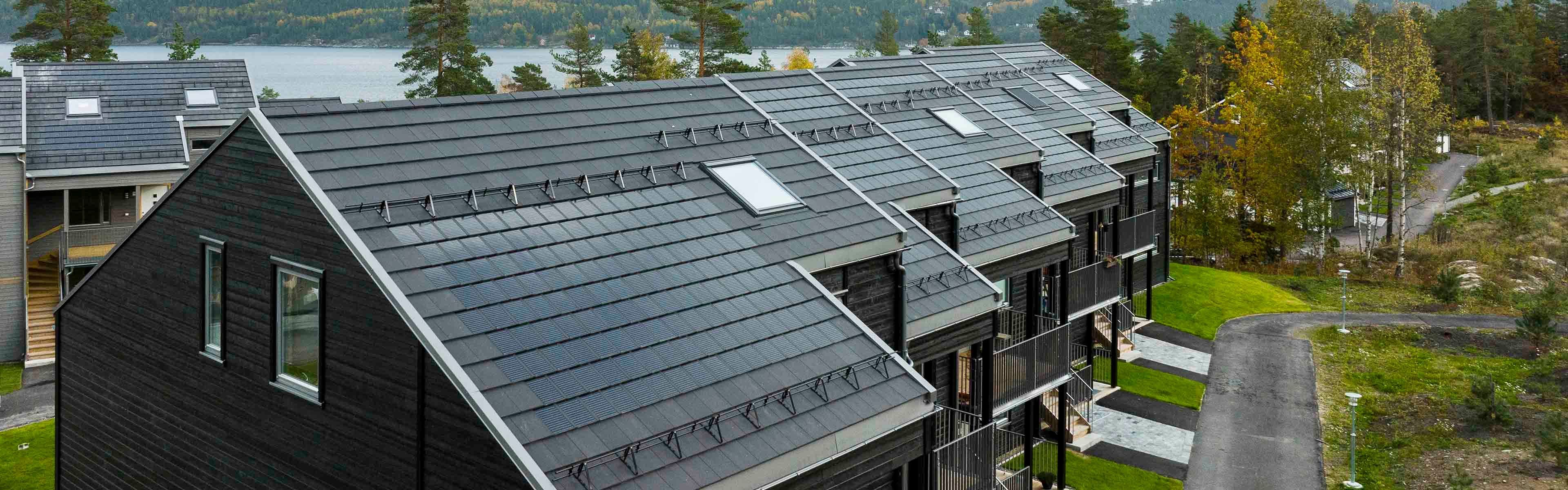 Svart rekkehus med solceller på tak.