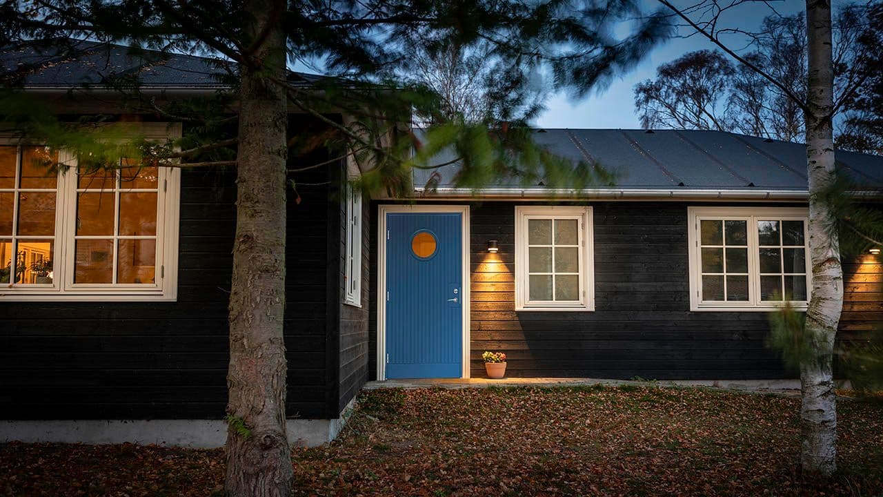koselig hytte med sort kledning og blå hyttedør
