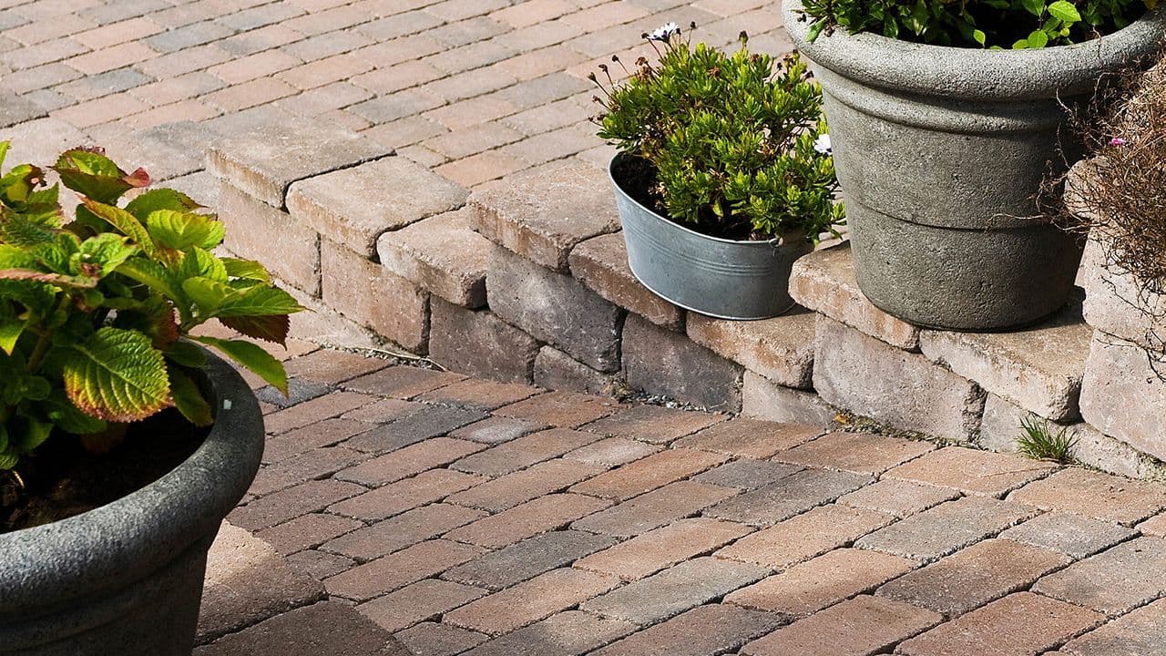 Aaltvedt Rådhus Brunmix belegningsstein som gangsti med blomsterpotter på mur på hver side.