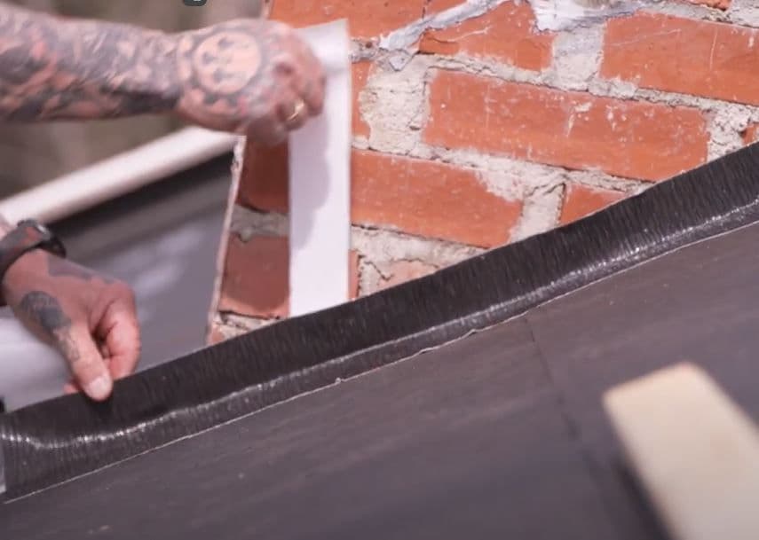 Hender som monterer tettebånd på tak.