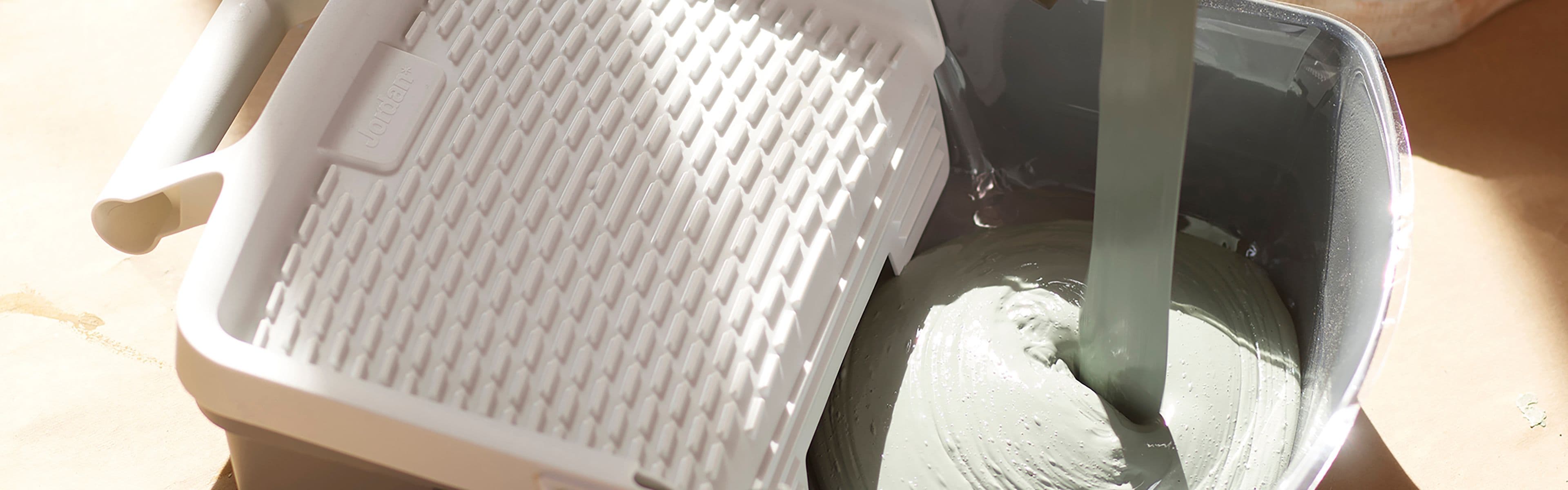 Malebrett som det helles lysegrønn maling oppi.