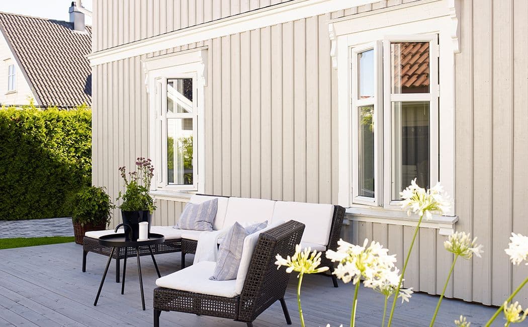 Uteplass med bord og stoler med hus i bakgrunnen