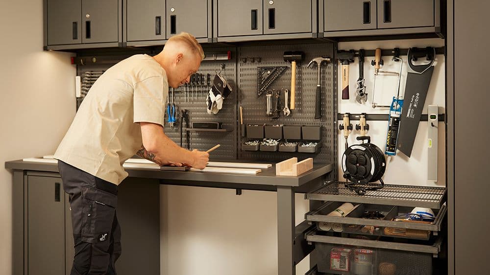 Mann som arbeider i garasje med garasjeinnredning.