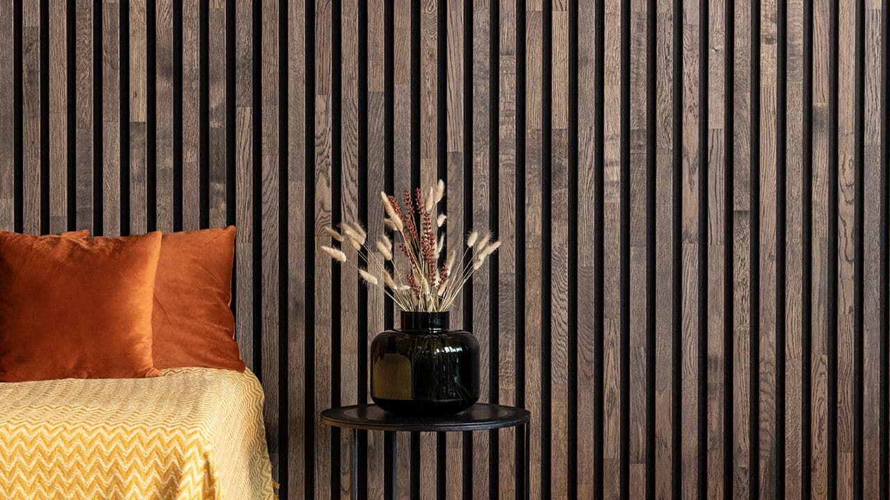 Spilevegg av spilepaneler bak sofa med oransje puter.