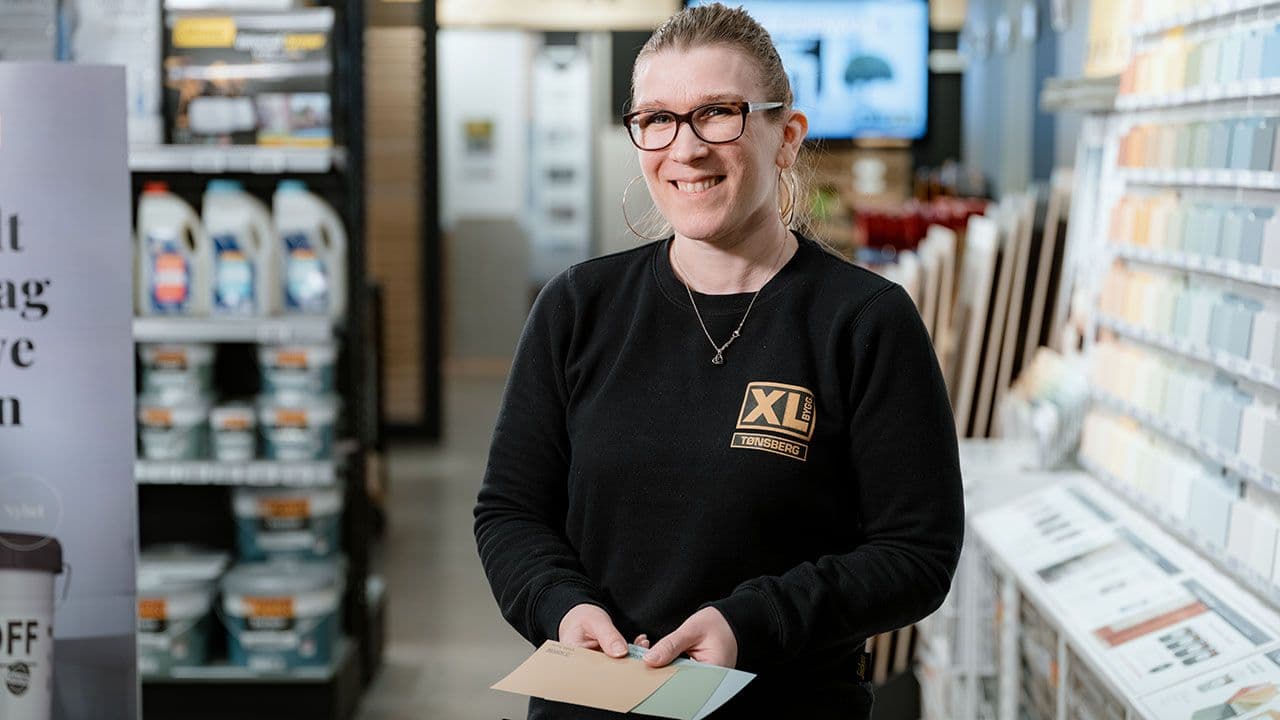 XL-BYGG ansatt som viser frem malingsprøver du kan male med ulik glansgrad.